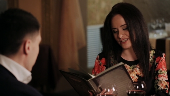 Lovely Couple Choosing Some Specialty From Menu At Restaurant