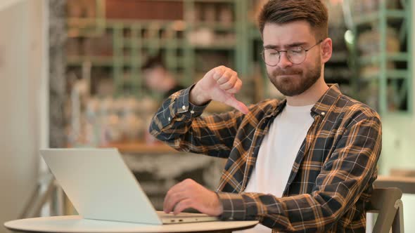 Thumbs Down By Young Man Working in Cafe  alt