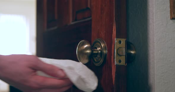 A hand cleaning and sanitizing a door knob covered in germs and virus with a disinfecting antibacter alt