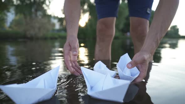 Man's Hand Launches Paper Boat on the Water and Pushing It Away