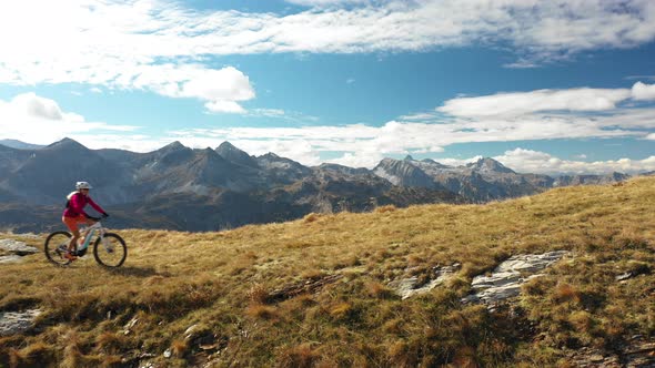 Aerial View Woman Biking With Electric Mountain Bike on Ridge Side View alt