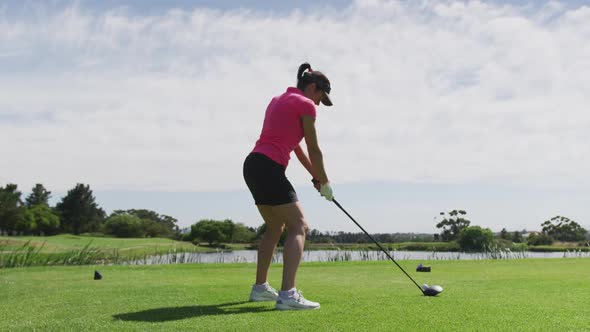 Caucasian woman playing golf taking a shot from bunker alt