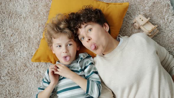 Portrait of Joyful Family Mom and Kid Having Fun Making Funny Faces Laughing at Home alt