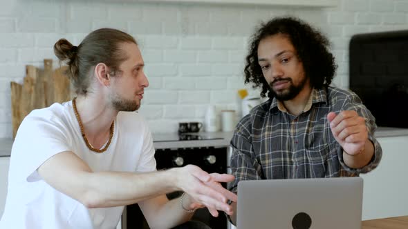 A European Man and an Asian Guy Work At Home, Use a Laptop and Tablet, Do Business Online in A Brigh alt