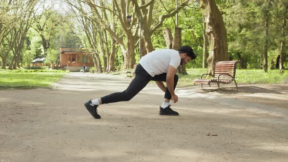 Sporty Young Man Dressed in Sport Clothes Doing Exercises for Stretching Body on alt