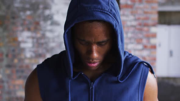 Portrait of african american man wearing hoodie sweating after exercise looking at camera in urban b alt
