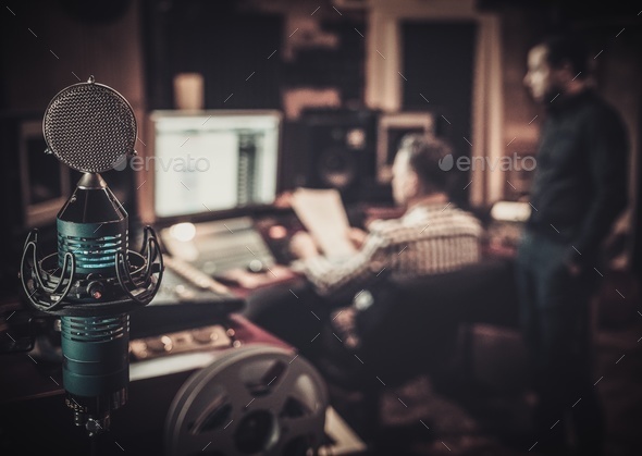 Sound engineer and producer working together at mixing panel in the boutique recording studio. - Stock Photo - Images