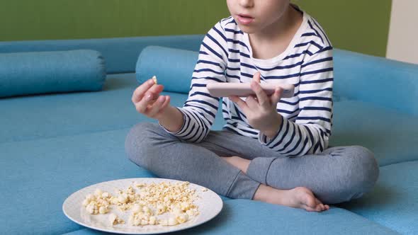Kid Eat Popcorn and Spending Time Online Using your Smartphone alt
