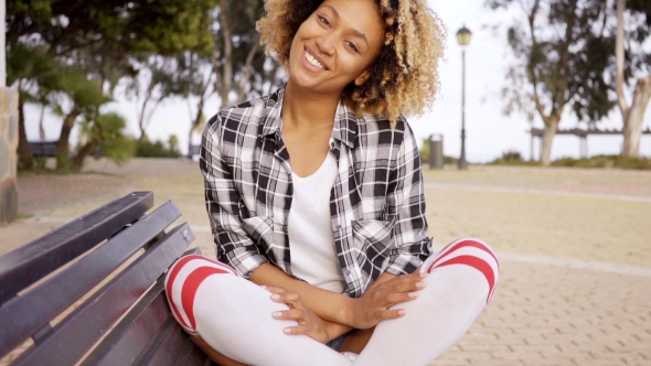 Young Woman With Crossed Legs On Bench alt