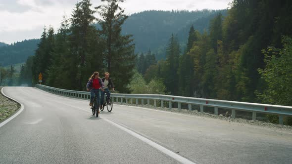 Millennials Riding Bikes Together in Mountains Landscape alt