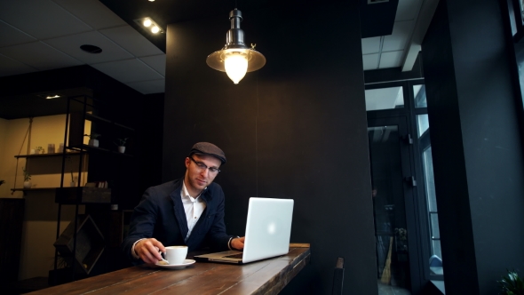 Young Man Drinking Coffee On The Street While Using Tablet Computer alt