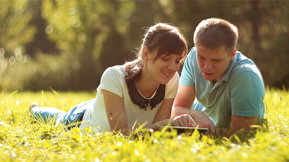 Young Couple Using Tablet Computer Touchscreen in Park