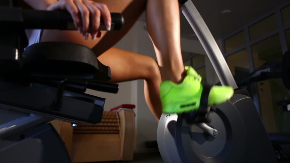 Female Legs Riding At Stationary Bike In The Gym