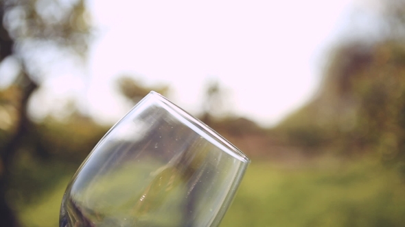 Hand Twists Transparent Empty Glass On The Background Of The Sun. alt