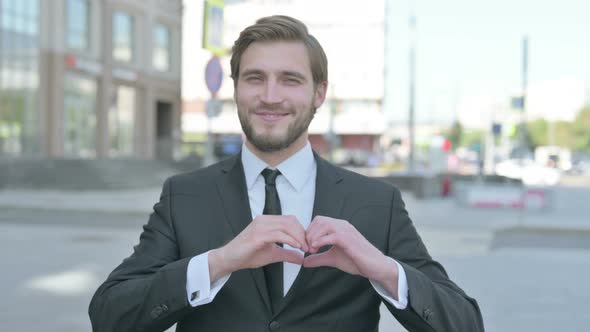 Loving Businessman Showing Heart Shape By Hands Outdoor alt