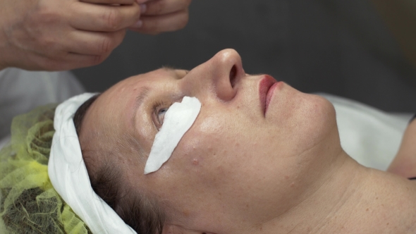 Cosmetologist Put Cotton Pad Under Eye Woman In Beauty Saloon. Permanent Dyeing  alt