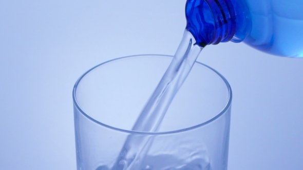 Pouring Water From Bottle Into Glass In Blue Toning