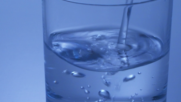 Filling a Glass With Water On Blue Background