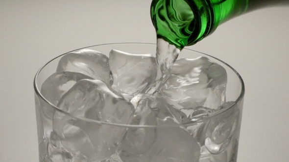 Mineral Water Being Poured Into Glass From Green Bottle