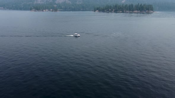 Drone crane shot of a pontoon boat driving from right to left on Payette Lake in McCall, Idaho. This alt