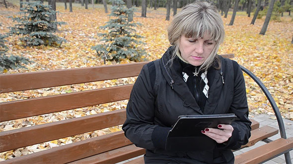 Woman in Autumn Park Working With the Tablet