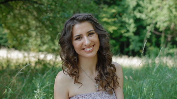 Caucasian Woman Sit In The Grass And Smile