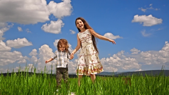 Girl And Boy Jumping In Green Field