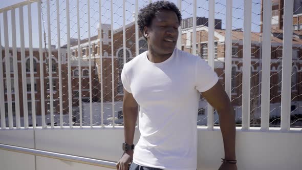 Tired African American Sportsman Leaning on White Metal Fence alt