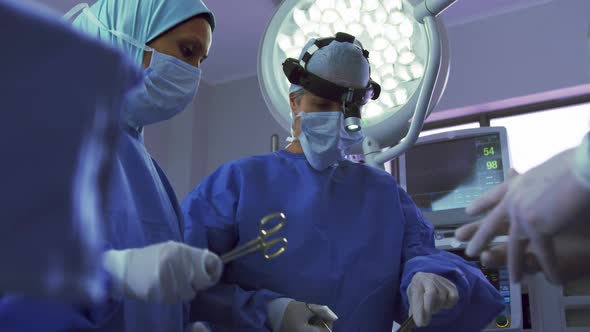 Low angle view of Middle-east female surgeon performing surgery in operation theater at hospital alt