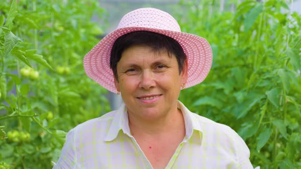 Pretty Happy Mature Gardener Woman with Pink Hat Looking at Camera alt