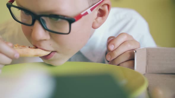 Hungry Boy in Shirt Eats Tasty Pizza at Green Plate Closeup alt