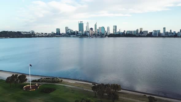 Aerial panoramic of Australian flag pole next to water, Perth city skyline in background alt