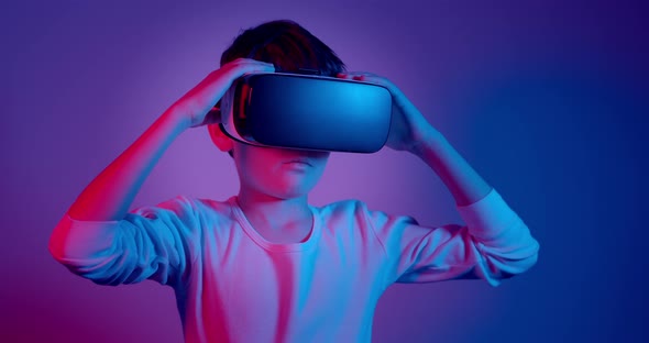 Boy Wearing VR Glasses Looking Around Under Neon Lights