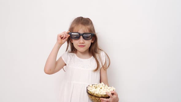 Girl with Glasses to Watch 3D Movies with Popcorn Stands Against White Wall alt