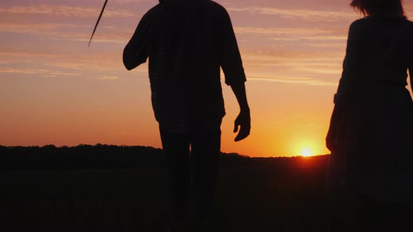 A Couple of Farmers Man and Woman Walking Away Into the Field at Sunset alt