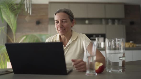 Woman Talking With Friends via Video Call on Laptop at Home