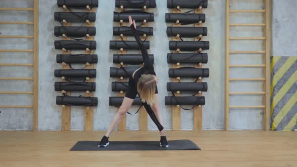 Young Athletic European Woman Doing A Stretching Exercise in the Gym, Dressed in Black Sportswear alt