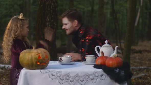 Side View Funny Little Girl and Man in Vampire Costume Gesturing Grimacing Scaring Each Other alt