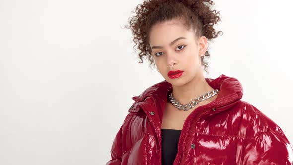 Young Woman with Red Lacquer Lips and Red Shiny Jacket on White in Studio