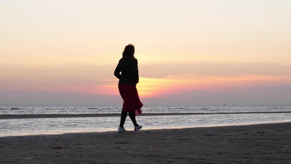 Woman walks alone on cold sea beach to clear her mind, windy weather