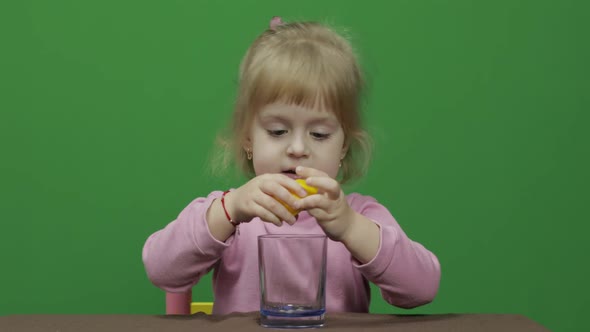 Beautiful Young Girl Squeezes Lemon Juice and Drinks It with a Grimace on Face alt