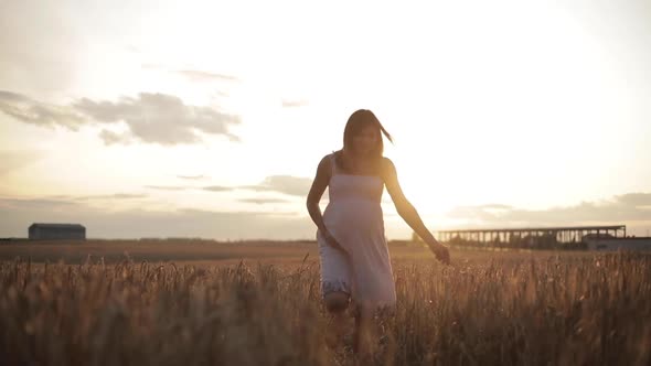 Pregnant Brunette Woman in White Dress in the Field