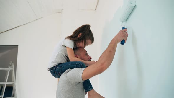 Caucasian Man and Girl Paint the Wall Daughter Sits on the Shoulders of Her Father and Paints the