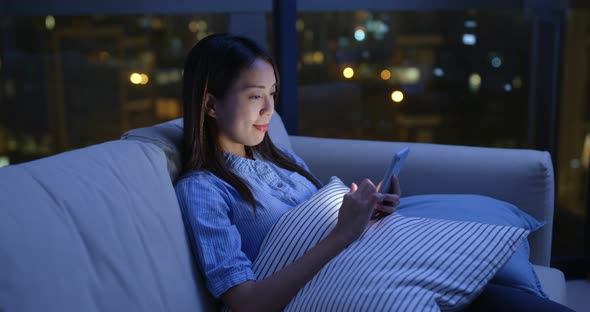 Woman use of mobile phone online at night inside home alt