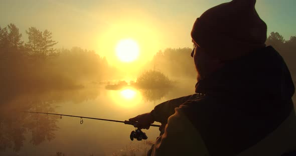 Unrecognizable Man Fishing in Lake at Dawn