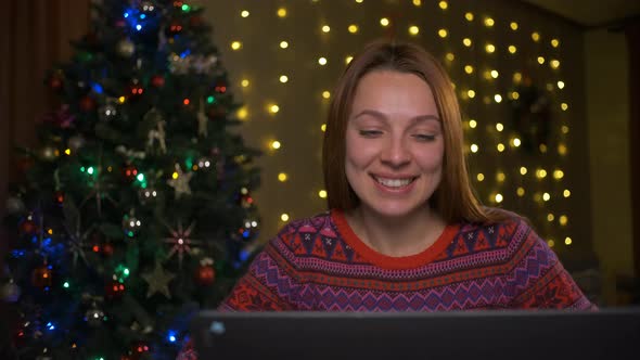 Young Pretty Woman Having Video Chat on Her Laptop at Home Near Christmas Tree