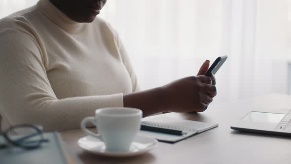 African American Businesswoman Using Mobile Phone Sitting In Office Cropped alt