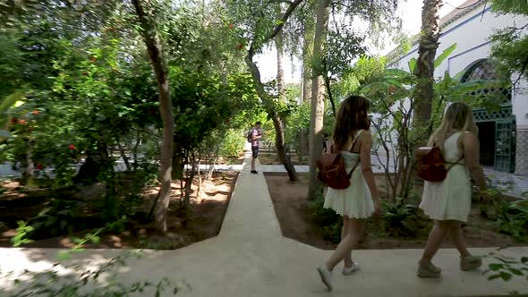 Two young girls dressed white walking in a garden alt