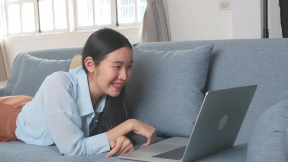 Woman Lying On A Sofa And Video Call With Friend In Home Living Room alt