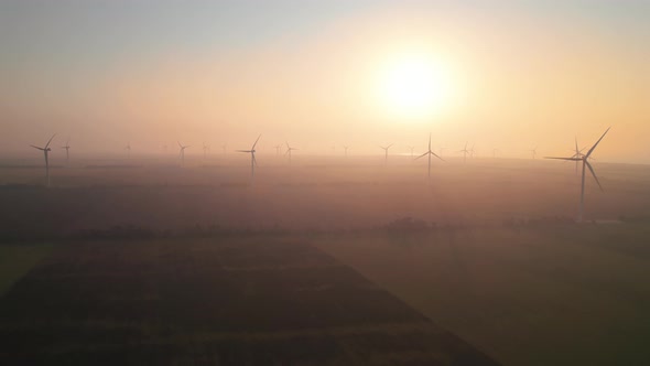 Windmills with rotating wings at sunrise or sunset or sunrise.